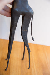 Dark patina finish on the back legs and tail of the vintage giraffe sculpture.