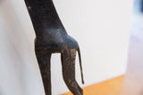 The carved wooden body and dark, textured patina of a vintage African giraffe.