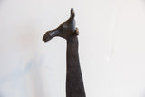 Profile of a vintage African giraffe's carved head with a dark, textured patina.