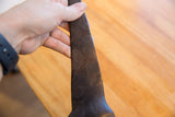 A hand holds the vintage African giraffe, highlighting its dark patina and carved texture.