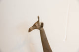 The sculpted head of a vintage African giraffe showing its aged, patinated metal finish.