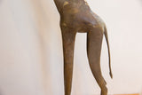 The sculpted hindquarters and tail of a vintage giraffe with aged metal patina.