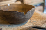 Vintage African wooden bowl close-up, showcasing its aged rim with chips and cracks.