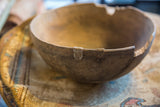 Aged wooden African bowl rim featuring a visible crack and metal repair.