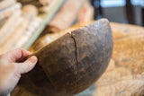 A storied crack running along the dark, rustic surface of a vintage wooden African bowl.