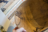 Vintage African wooden bowl interior with prominent crack and zig-zag metal repairs.