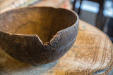 Aged cracks and a chipped rim show the character of a hand-carved vintage wooden bowl.