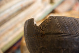 A weathered chip and crack along the rim of the vintage hand-carved wooden bowl.