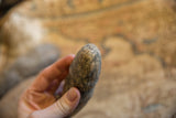 Close-up on the mottled, weathered stone texture of a primitive African tool.