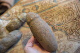 A primitive Neolithic African stone tool held to show its shape and coarse, weathered texture.