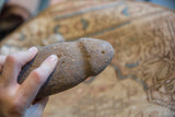 The primitive stone tool's scale and weathered, porous texture shown in hand.