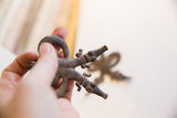 Vintage double crocodile pendant held in hand, highlighting its dark patina and etched texture.