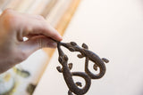 A hand holds the vintage double crocodile pendant, showing its dark textured finish.