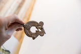Vintage African pendant with lizard motif held to show its scale and surface patina.