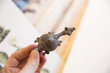 A vintage African turtle pendant showing its profile and textured metal surface.