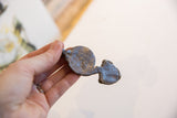 A vintage African snake pendant held to show its rustic metal patina and scale.