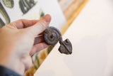 A hand holding the vintage African snake pendant, showing its scale and texture.