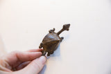 A hand holding the vintage turtle pendant, showing its scale and aged metal texture.