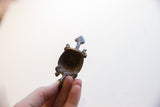The hollowed interior of the cast metal turtle pendant revealing its dark aged patina.