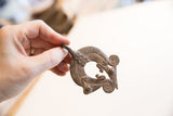 Vintage African chameleon lizard pendant's textured dark metal surface.