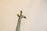 Head of a vintage African giraffe sculpture showing aged, mottled surface texture.