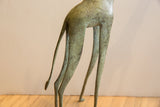 Aged patina and textured finish on the slender legs and tail of a vintage giraffe.