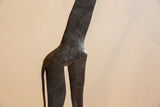 Hand-carved patterns on the dark, textured body of a vintage African giraffe sculpture.