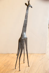 Full view of the vintage African giraffe's slender form and textured dark metal surface.