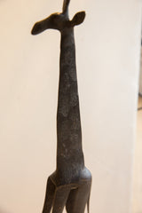 Dark, textured patina on the long neck and head of a vintage giraffe sculpture.