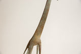 Detail of vintage African giraffe neck showing textured bronze with green patina and etched patterns.