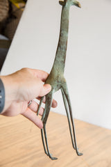 Hand holding vintage African giraffe, showing verdigris patina and detailed textured spots.