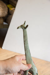 Green-blue patina on the vintage African giraffe's textured head and long neck.