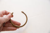 Curved form of the antique bronze snake cuff showing hand-stamped details.