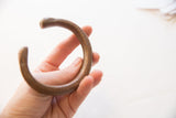 The substantial thickness and smooth, curved form of the antique copper alloy cuff.