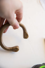 Hand holding the antique bronze snake cuff to display its open shape and patina.
