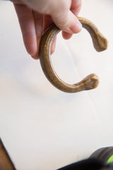 Antique African bronze snake cuff held in hand, showing its curved shape and scale.