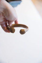 Antique African bronze snake cuff held to show its scale and open design.
