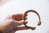 Antique African bronze snake cuff bracelet held in hand for scale.