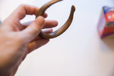 The smooth, aged patina on the curved form of an antique bronze cuff.