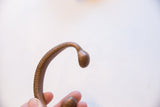 Incised textural details and smooth bulbous end of an antique bronze snake cuff.