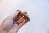 Antique bronze cuff bracelet held in hand showing its scale and smooth curve.