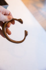 Profile view of the antique copper alloy snake cuff's open C-shape.