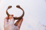 Antique copper snake cuff held in hand, showing its rounded form and patina.