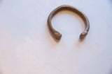 Stylized serpent heads with incised details on an antique bronze African cuff.