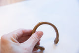 A visible surface crack and aged patina on the antique bronze bracelet.