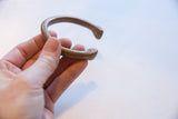 Antique bronze snake cuff held in hand, showing its aged patina and shape.