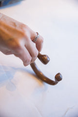 A hand holding the antique copper alloy cuff to show its sculptural form.