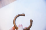 Etched markings and aged patina on the rounded terminal of an African bronze cuff.