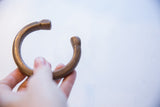 Angled view of an antique bronze snake cuff showing its open form and etched ends.