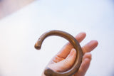 A hand holding the thick, antique bronze cuff to demonstrate its substantial size.